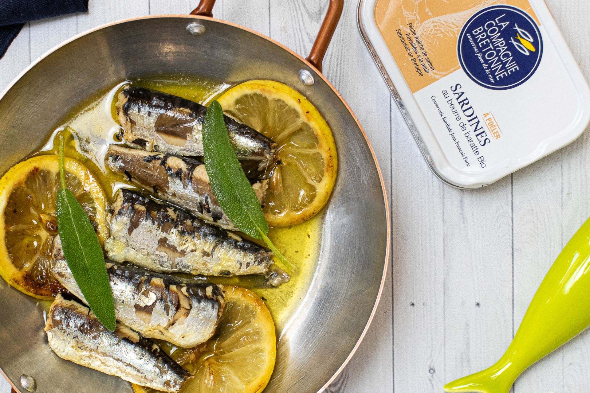 foto de uma receita de sardinhas com rodelas de limão em uma panela e uma lata de sardinha em conserva gourmet da La Compagnie Bretonne, fornecedora parceira da Fui ao Mar no Brasil